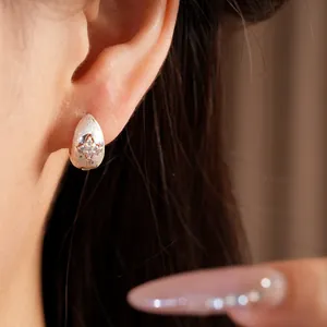 Detailed close-up of minimalist frosted silver teardrop hoop earrings featuring zircon star