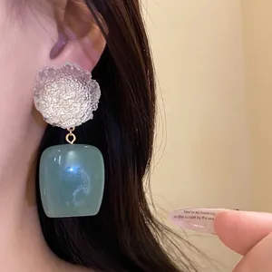 Vintage resin flower earrings with a square sea-green pendant shown on Asian model