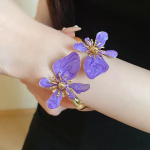 Vintage-Armreif mit lila Emaille-Blumen in Gold-Finish, am Arm des Models getragen.