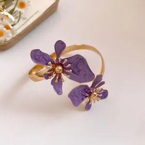 Nahaufnahme einer lila emaillierten Blumen-Armspange mit goldener Metalloberfläche
