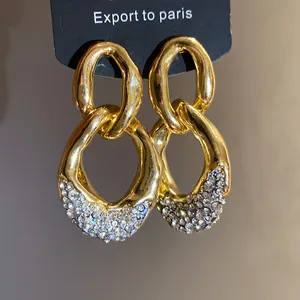 Dettaglio di orecchini a cerchi dorati con pavé di strass scintillanti incastonati.