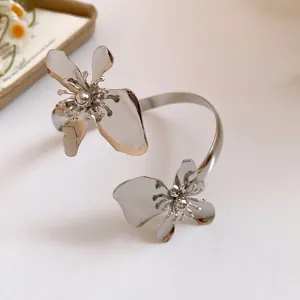 Detailansicht eines eleganten silbernen Metall-Armreifs mit zwei großen Blumenakzenten