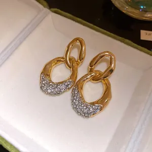 Primo piano di lussuosi orecchini a catena d'oro con scintillanti dettagli in strass