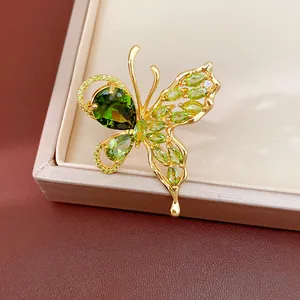 Detailed view of a gold-plated butterfly earring set with sparkling green zircons.