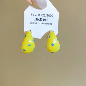 Detail view of stylish yellow enamel C-shaped earrings with blue polka dot patterns