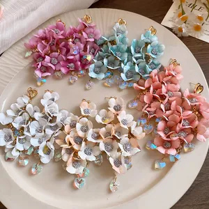 Detailed shot of fabric flower tassel earrings with heart crystal pendants in various colors