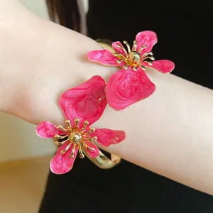 Nahaufnahme der retro pinkfarbenen Emaille-Blumen-Armspange mit eleganten goldenen Details.