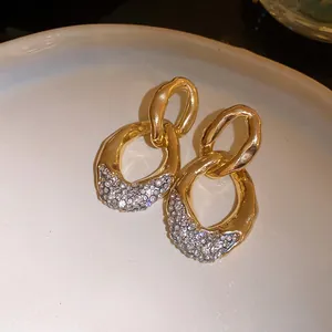Dettaglio macro di eleganti orecchini dorati con decorazioni in strass scintillanti.
