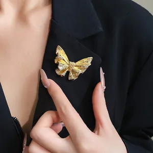 Close-up of elegant 18k gold plated butterfly brooch with sparkling stones on black blazer