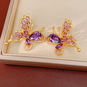 Detailed macro view of gold-plated butterfly earrings with sparkling purple zirconia stones.