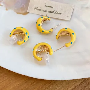 Detailed macro shot of yellow polka dot C-shaped earrings and non-pierced clip-on styles