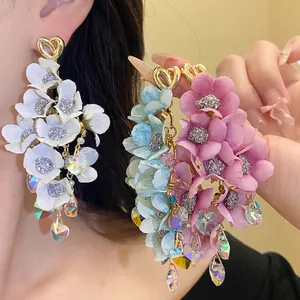 Close-up of colorful fabric flower tassel earrings with sparkling heart pendants.