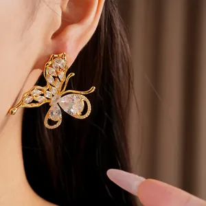 Close-up of gold-plated butterfly earrings with sparkling cubic zirconia on ear.