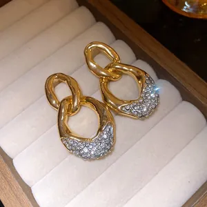 Primo piano di eleganti orecchini a pendente dorati con accenti di strass.
