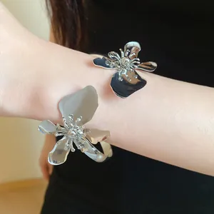 Nahaufnahme eines silberfarbenen Metall-Armreifs mit großen Blumenmotiven