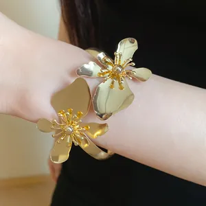 Detaillierte Ansicht eines eleganten goldenen Metall-Armreifs mit zwei Blumen am Arm