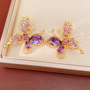Detailed close-up of gold-plated butterfly stud earrings with sparkling purple CZ stones.