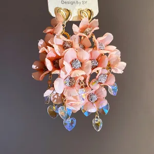 Detail view of pink fabric flower dangle earrings with crystal heart pendants