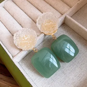 Macro view of vintage green resin square drop earrings with white textured flower detail