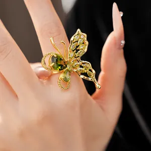 Close-up of exquisite gold plated butterfly ring with green cubic zirconia stones.