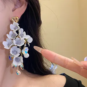 Detailed view of long white fabric flower earrings with iridescent crystal hearts.