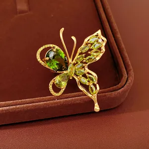 Detailed macro view of a luxury gold-plated butterfly jewelry piece with green gemstones