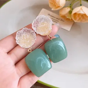 Close-up of vintage resin earrings with crinkled flowers and green square pendants