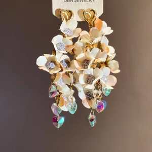 Close-up of elegant fabric flower tassel earrings with shimmering crystal hearts