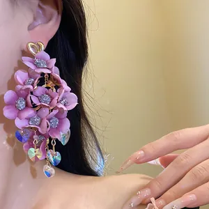 Close-up of elegant pink fabric flower tassel earrings with crystal hearts on an Asian model
