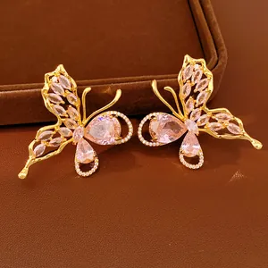 Detailed macro shot of gold-plated butterfly stud earrings with pink zircon stones