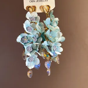Detailed macro shot of light blue fabric flower earrings with crystal heart charms