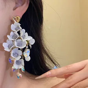 Detailed view of elegant white fabric floral tassel earrings with iridescent heart charms