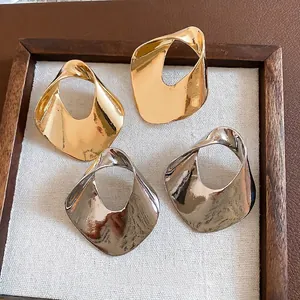 Pair of chunky geometric hollow metal earrings in gold and silver finish on display