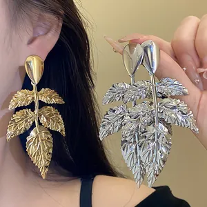 Vista dettagliata di orecchini pendenti color oro e argento con design a foglia.