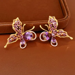 Detailed view of gold-plated butterfly stud earrings inlaid with purple marquise zirconia stones.