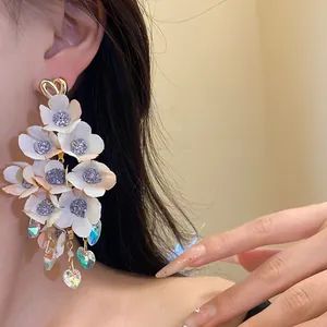 Detail view of cream fabric flower earrings with sparkling centers and iridescent crystals.