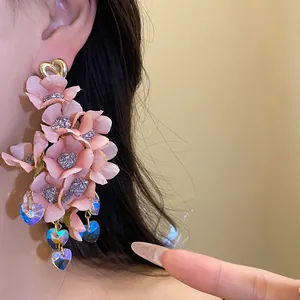 Detailed view of pink fabric flower tassel earrings with blue heart crystals