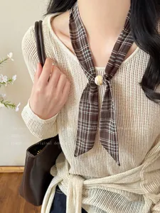 Close-up of a brown plaid twilly scarf with a marble ring buckle on a beige mesh sweater