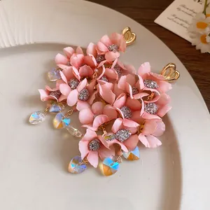 Detailed macro shot of pink fabric flower tassel earrings with iridescent heart charms