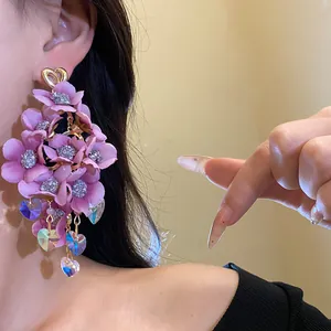 Close-up of large purple fabric flower tassel earrings on model wearing silver needle studs.