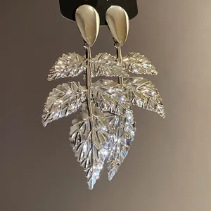 Dettaglio degli orecchini a foglia in metallo argentato con finitura stropicciata