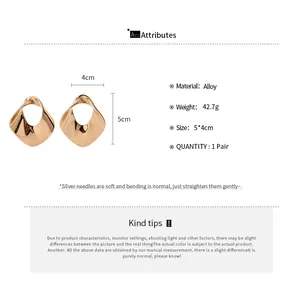 Detail view of gold geometric hollow metal earrings with size and material specifications