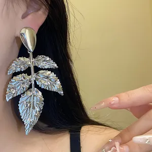 Primo piano dettagliato di orecchini a pendente a foglia d'argento su una modella