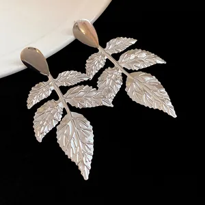 Dettaglio ravvicinato di orecchini a foglia in metallo argento con texture