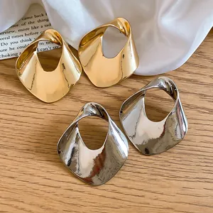 Detail shot of oversized geometric hollowed-out metal earrings in gold and silver