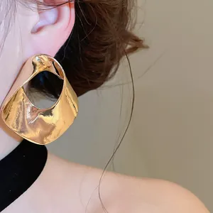 Close-up of an exaggerated gold geometric hollow earring worn on a model's ear