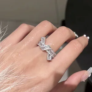Primer plano de un anillo de nudo plateado con circonitas brillantes en una mano.