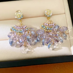 Close-up of elegant vintage-style fan-shaped tassel earrings with purple crystals in a box