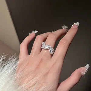 Detalle de cerca de un anillo de nudo plateado con circonitas brillantes en la mano