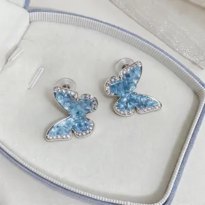 Close-up of blue butterfly earrings with sparkling zircon borders in a jewelry box